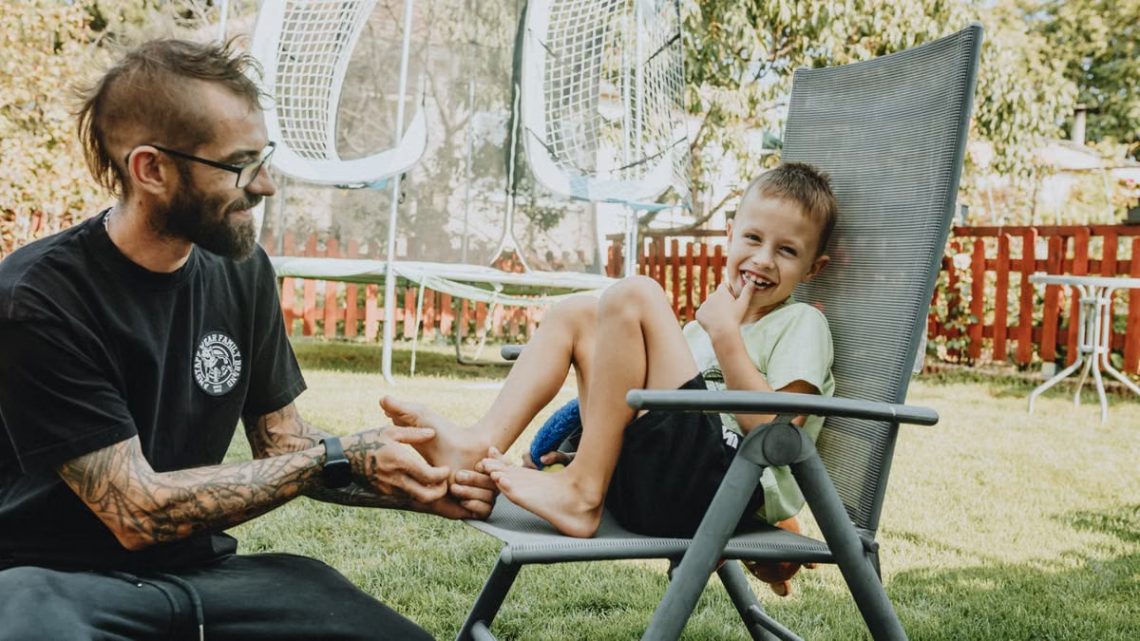 Playful interaction between a father and son in a sunny backyard setting.